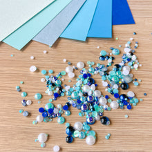 Load image into Gallery viewer, Color swatches of blue paper and decorative pearl gem stones on a wooden surface