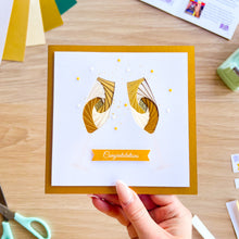 Load image into Gallery viewer, Hand holding a card with gold and white champagne flute design on a wooden surface