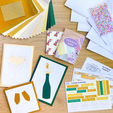 Load image into Gallery viewer, Collection of greeting cards, envelopes, embellishments and an iris folding guide on a wooden surface