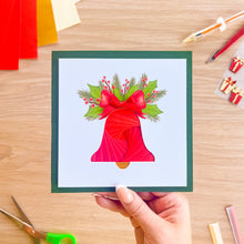 Load image into Gallery viewer, A greeting card with a red iris fold bell, red bow and green holly leaf embellishments.