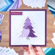 Load image into Gallery viewer, Hand holding a card with a purple Christmas tree design on a wooden surface.