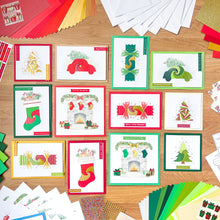 Load image into Gallery viewer, Collection of Christmas-themed iris folded greeting cards on a wooden surface with additional craft materials.