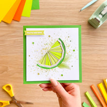 Load image into Gallery viewer, Hand holding a card with a lime iris folding design on a wooden table with craft supplies.