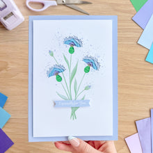 Load image into Gallery viewer, Greeting card with floral design held by a hand on a wooden surface with stationery items.