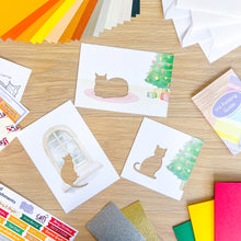 Load image into Gallery viewer, Collection of cat-themed card apertures and craft materials on a wooden surface