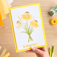 Load image into Gallery viewer, Hand holding a card with yellow flowers and 'Birthday Wishes' text on a wooden surface.