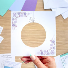 Load image into Gallery viewer, Round decorative aperture card with snowflake patterns, held by a hand.
