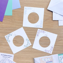 Load image into Gallery viewer, Iris folding patterns with circular cutouts on a wooden surface