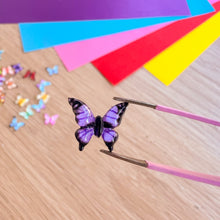 Load image into Gallery viewer, Butterfly-shaped gem on a wooden surface with colourful paper in the background