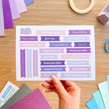 Load image into Gallery viewer, Sheet of decorative phrases on a wooden surface with a hand holding it.