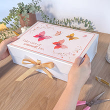 Load image into Gallery viewer, Gift box with butterfly design and message, held by a person on a wooden surface.
