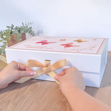 Load image into Gallery viewer, Person tying a ribbon on a decorative box with floral designs.