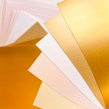 Load image into Gallery viewer, A close-up fan of metallic and matte paper sheets in warm tones, including vintage gold, pale gold, ivory, cream and vanilla tones.