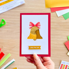 Load image into Gallery viewer, A hand holds a red greeting card with an iris fold gold bell with a printed red bow and a 'Just for you' greeting.