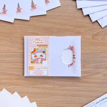 Load image into Gallery viewer, A packaged mini pumpkin aperture card pack sits on a light wood tabletop, surrounded by folded white paper sheets and matching paper pieces. The package front shows the text 'Mini Pumpkin' and a small example photo of the finished card craft.