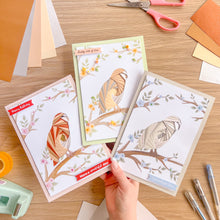 Load image into Gallery viewer, Bird-themed iris folding greeting cards on a wooden table with stationery items.