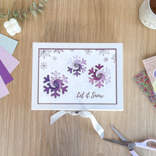 Load image into Gallery viewer, Gift box with purple snowflakes and 'Let it Snow' text on a wooden surface with craft items.