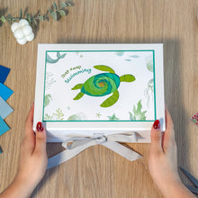 Load image into Gallery viewer, Box with a turtle design and 'Just Keep Swimming' text held by hands on a wooden surface.