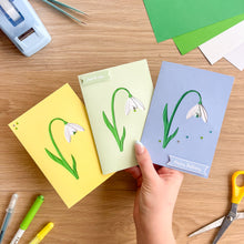 Load image into Gallery viewer, Three greeting cards with iris fold floral designs on a wooden table with stationery items.