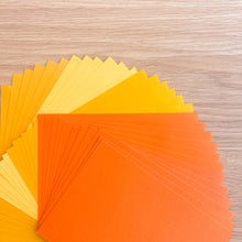 Load image into Gallery viewer, Stack of orange and yellow paper sheets on a wooden surface