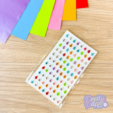 Load image into Gallery viewer, Sheet of colorful teardrop-shaped stickers on a wooden surface with colorful paper sheets.