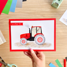 Load image into Gallery viewer, A handmade iris fold greeting card featuring a red and black tractor with a 'Especially for You' banner, held by a hand over a wooden desk with craft supplies.