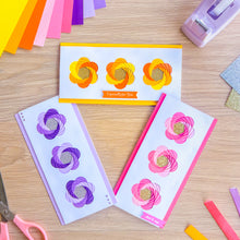 Load image into Gallery viewer, Floral iris fold cards on a wooden surface with craft supplies.