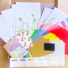 Load image into Gallery viewer, Collection of craft materials including cardstock, stickers, and a die-cutting guide on a wooden surface.