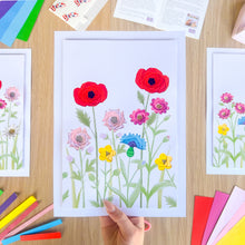 Load image into Gallery viewer, Colorful floral iris folding picture held by a hand on a wooden table with craft supplies.