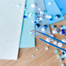 Load image into Gallery viewer, Close-up of a craft project with tweezers and colorful pearls on a wooden surface.
