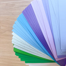 Load image into Gallery viewer, Color swatch card with various shades of blue, green, and purple on a wooden surface.
