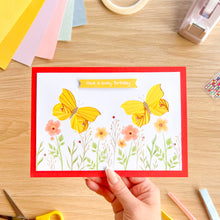 Load image into Gallery viewer, Hand holding a birthday card with yellow iris folding butterflies on a wooden table.
