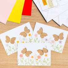 Load image into Gallery viewer, Three butterfly aperture cards on a wooden table with other card-making materials
