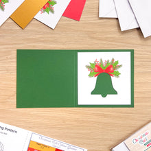 Load image into Gallery viewer, A bell cut-out on a dark green card blank.
