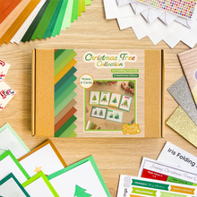 Load image into Gallery viewer, A Christmas Tree Collection Iris Folding Card Kit by Pretty Paper Co. is displayed in a styled flat-lay on a light wood desk, surrounded by colorful paper stacks, finished card borders, and instruction sheets.
