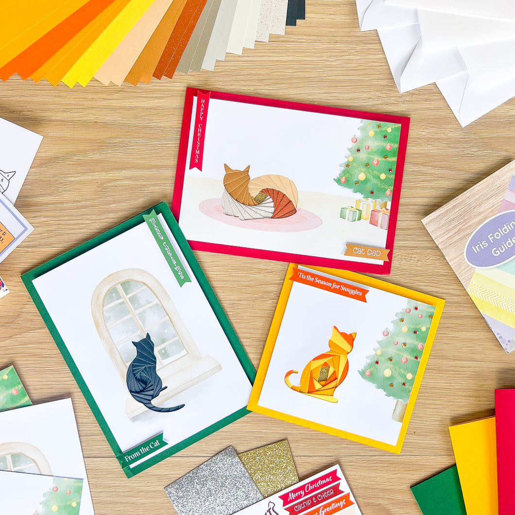 Collection of greeting cards with cats and Christmas trees on a wooden surface.