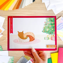 Load image into Gallery viewer, Hand holding a Christmas card with a cat design, surrounded by colorful paper strips.
