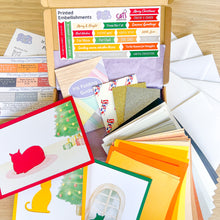 Load image into Gallery viewer, Collection of printed embellishments and greeting card-making materials on a wooden surface
