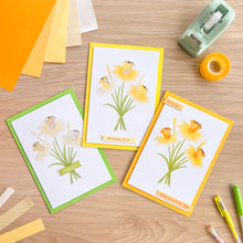 Load image into Gallery viewer, Three greeting cards with floral daffodil designs on a wooden surface with stationery items.
