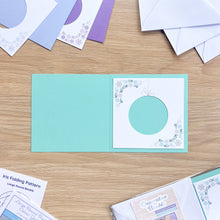 Load image into Gallery viewer, Open card with decorative round design on a wooden surface with other cards and papers.
