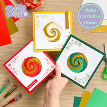 Load image into Gallery viewer, Handmade cards with spiral designs on a wooden table with crafting tools.
