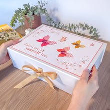 Load image into Gallery viewer, White box with butterfly design and &#39;take care of yourself, too&#39; text held by hands on a wooden surface with plants in the background
