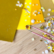 Load image into Gallery viewer, Close-up of tweezers with small gems on a wooden surface
