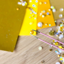 Load image into Gallery viewer, close-up of a yellow gold pearl held by tweezers
