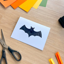 Load image into Gallery viewer, A greeting card with a black iris fold bat on a wooden surface surrounded by craft supplies
