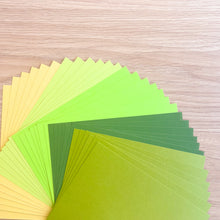 Load image into Gallery viewer, Stack of green and yellow paper sheets on a wooden surface
