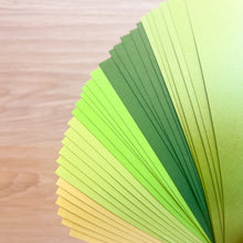 Load image into Gallery viewer, Stack of green and yellow paper sheets on a wooden surface

