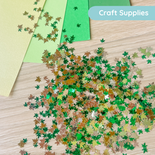 Load image into Gallery viewer, Colorful leaf-shaped confetti on a wooden surface with craft supplies in the background.
