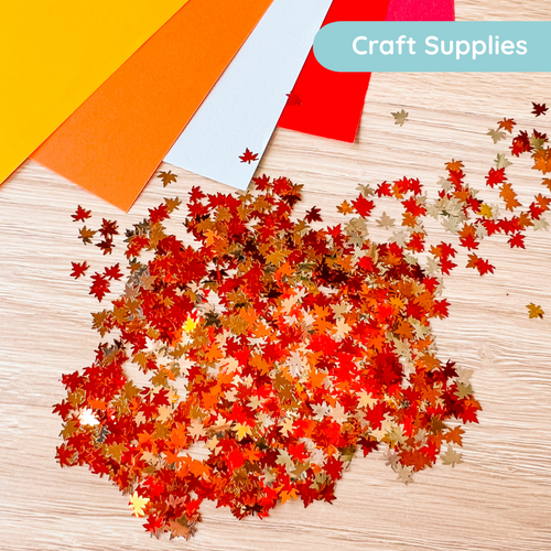 Colorful autumn leaf craft supplies on a wooden surface with craft paper in the background.