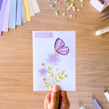 Load image into Gallery viewer, A purple mini iris fold butterfly on a card with printed purple flowers, resin flowers and 'Just to Say' greeting
